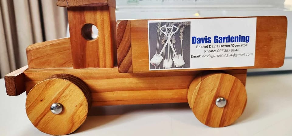Wooden toy truck displaying the Davis Gardening business card with the crossed-spades logo