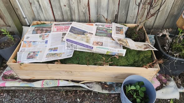 Finished raised garden bed layered with newspaper over grass clippings, ready for soil and planting